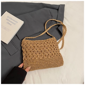 Close-up of handmade woven straw crossbody bag with floral pattern and natural texture