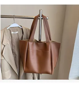 Close-up of brown leather tote bag featuring a front pocket and dual straps on hanger