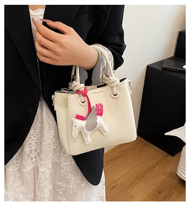 Detail of a beige pebbled leather bucket bag with a horse charm accessory for women
