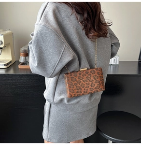 Dettaglio della borsa clutch leopardata vintage con catena metallica sul tavolino da caffè