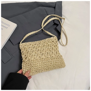 Detail of hand-woven beige straw bag with hollow star pattern and shoulder strap