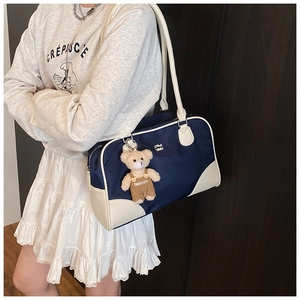 Détail d'un sac bowling rétro en nylon bleu marine et cuir crème avec charme d'ours