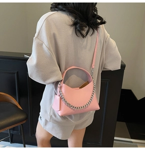 Pink lychee texture bucket bag with silver chain detail on model's back in gray set