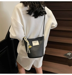 Détail du sac seau noir en cuir foulonné avec étiquette et pendentif ours doré