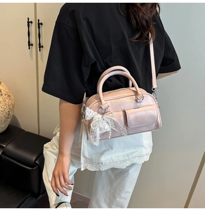 Detail view of light pink bowling bag with lace bow and pearl charm worn as crossbody