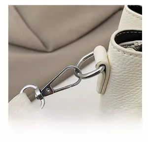 Close-up of polished silver metal hooks and D-ring on cream pebble leather bucket bag