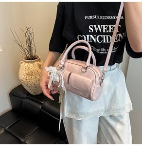 Detail of pink Boston bag with lace bow pendant and pearl charm decoration