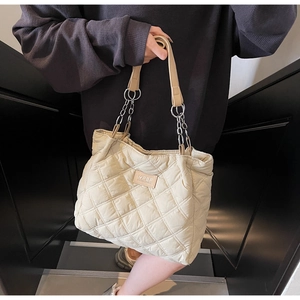 Detail der cremeweißen Stepptasche mit HPSF-Lederaufnäher und Kettenriemen