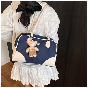 Détail du sac à bandoulière bleu et crème avec breloque ours et longues lanières