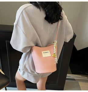 Détail du sac seau rose en cuir grainé avec étiquette HAMIROO et charm chien doré