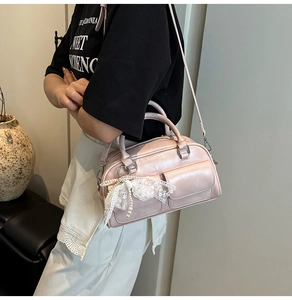 Close-up of pink faux leather bowling bag featuring a lace bow and pearl charm