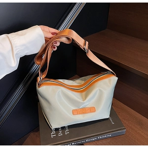 Detailansicht der Nylon-Beuteltasche mit orangem Lederbesatz und breitem Stoffgurt