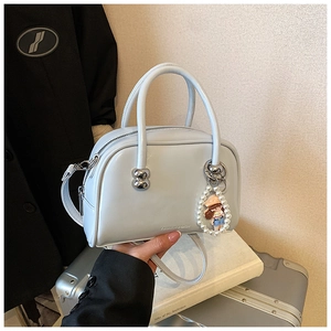 Detail of light blue Boston bag featuring silver accents and pearl charm on leather