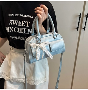 Close-up of light blue bowling bag with lace bow, pearl pendant and metal hardware detail