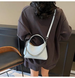 Detail view of light blue leather handbag with silver chain strap worn by a model