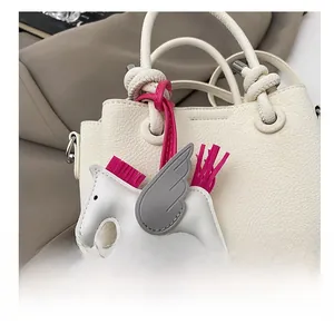 Detail view of the white leather pegasus charm with rose tassel on a bucket handbag
