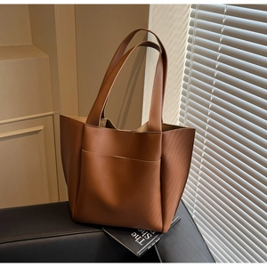 Close-up of caramel brown leather tote bag with front pocket and elegant shadow lighting