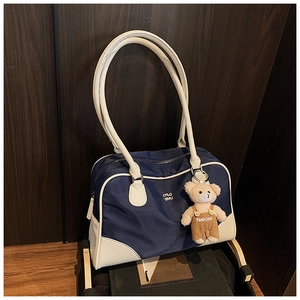 Détail d'un sac cabas bleu marine et beige avec un ourson sur fond de bois sombre