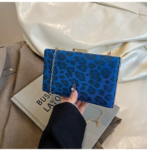Dettaglio della pochette da sera blu maculata con catena dorata e chiusura a scatto