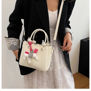 Close-up of cream pebble leather bucket bag with top handles and unicorn charm
