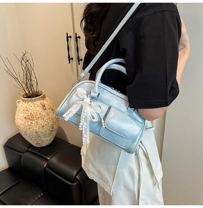 Detailed close-up of pearl blue leather bag featuring lace bow and pearl pendant