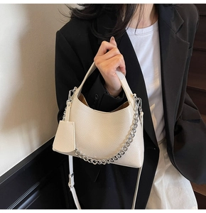 Detail of cream lychee texture leather bucket bag with silver chain strap and top handle