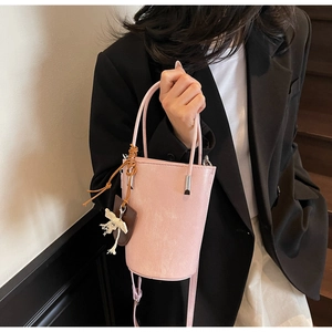 Pink bucket bag with tassels shown on model in a minimalist interior setting