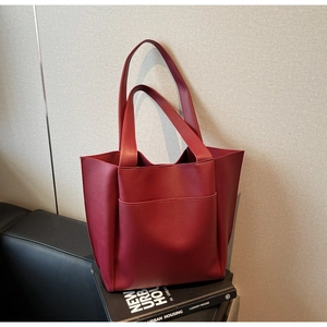 Detail of burgundy leather tote bag with front pocket placed on books for urban style
