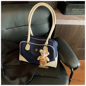 Détail du sac bowling en toile marine avec bordure en cuir beige et breloque ourson