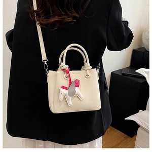 Detail of off-white bucket bag with lychee texture and creative horse charm on model