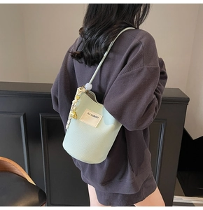 Détail du sac seau vert clair avec texture litchi et décor de poignée tissée