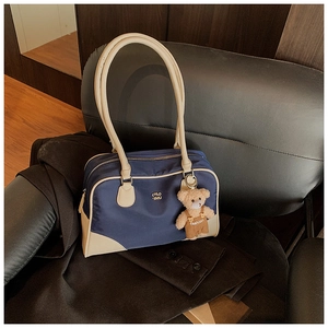 Détail du sac bowling en nylon bleu avec finitions en cuir blanc et breloque ourson