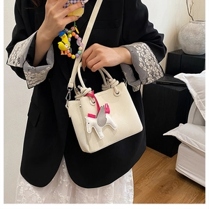 Detail of off-white mini tote bag with litchi texture and cute horse charm
