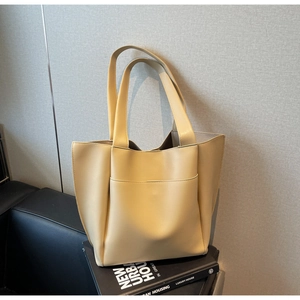 Detail view of large cream tote bag with exterior pocket on minimalist props