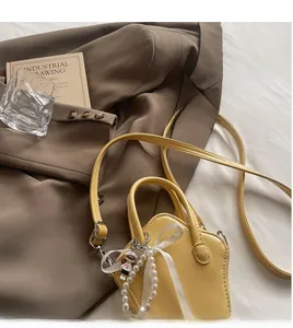 Detailed view of yellow star-shaped mini bag with pearl charms and smooth shoulder strap