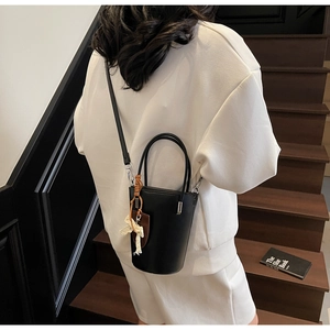 Detailed view of a black bucket bag with a lace bow and adjustable shoulder strap