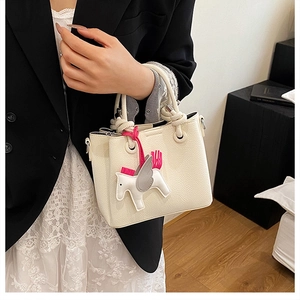 Detailed close-up of cream textured leather handbag featuring a colorful Pegasus charm