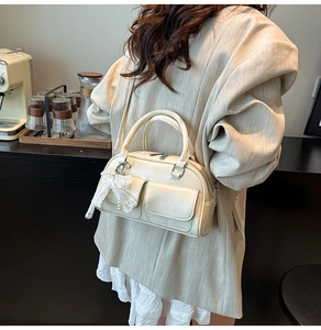 Detail view of cream crossbody bag with lace bow pendant and side pocket design