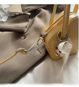 Detail of light yellow star bag featuring glossy hardware and silk bow accessory