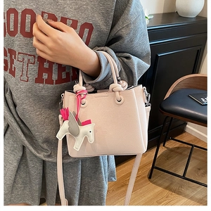 Detail view of pink leather bucket bag with pegasus charm and detachable shoulder strap