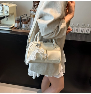 Detail of cream white bowling bag featuring two small front pockets and a lace bow charm