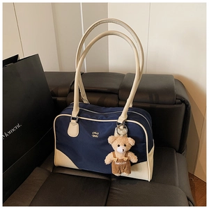 Détail du sac bowling vintage bleu marine avec accents beiges et breloque ourson