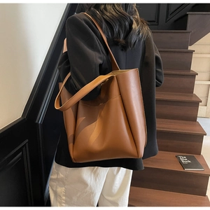 Detail of soft brown leather tote bag with wide shoulder straps and side stitching