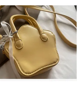 Detail of yellow star-shaped PU leather bag featuring silk ribbon and pearl charms