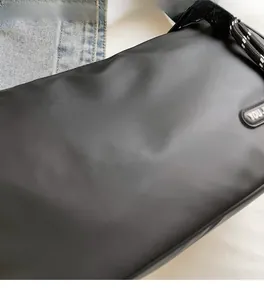 Close-up of durable black nylon crossbody bag fabric on blue denim background