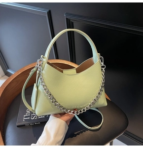 Detail view of pistachio green bucket bag with lychee leather texture and silver chain strap