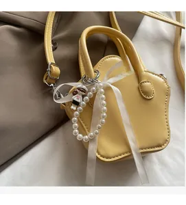 Detail of yellow star bag featuring pearl chain, ribbon, and trendy doll charm