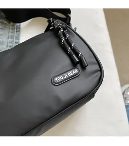 Detail shot of black nylon crossbody bag featuring brand logo and woven texture zipper pull