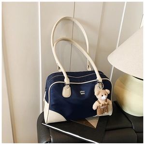 Detailed view of a navy and beige Boston bag with a bear doll and CHLO print on a book