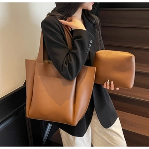 Brown leather tote bag and zipper pouch set shown with decorative front pocket detail